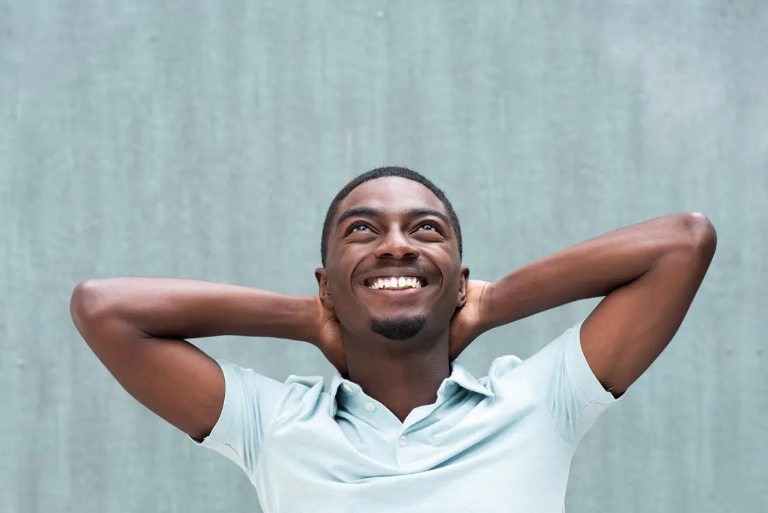 Confident man smiling with hands behind his head